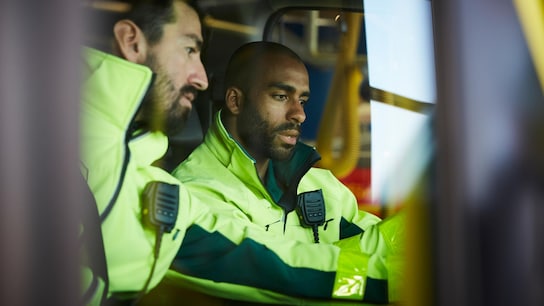 Paramedics discussing while sitting in ambulance at parking lot