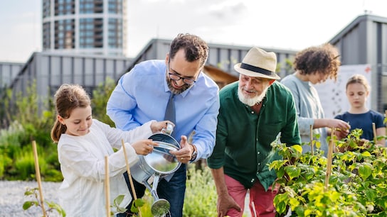 Neighbours taking care together of their community garden in a city. 